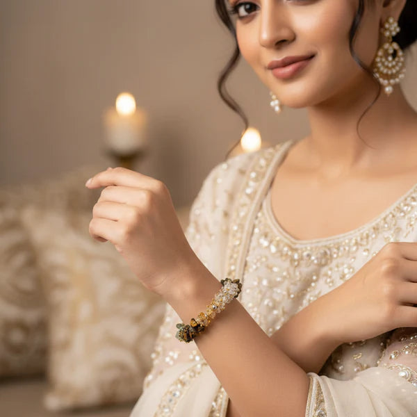 Woman wearing a white embroidered outfit with jewelry, holding a decorative item.